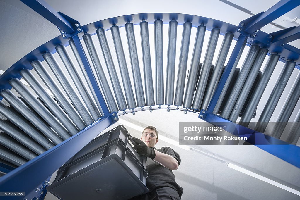 Low angle view of apprentice with crates on production line