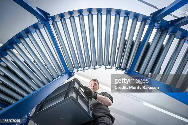 low angle view of apprentice with crates on production line - factory wide angle stock pictures, royalty-free photos & images
