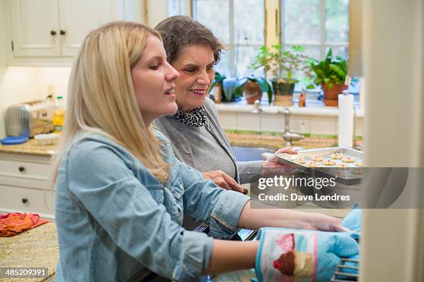 senior woman and granddaughter baking biscuits in oven - gran londres stock pictures, royalty-free photos & images