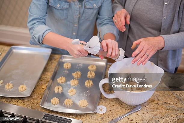senior woman and granddaughter piping biscuits onto baking tray - gran londres stock pictures, royalty-free photos & images