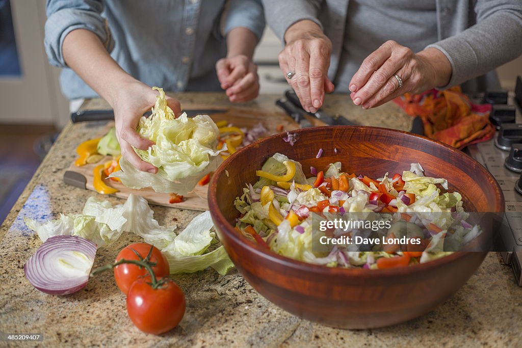 Senior woman and granddaughter chopping vegetables for salad