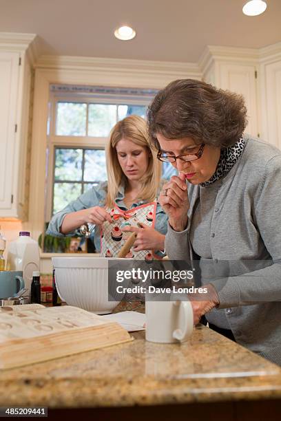 senior woman and granddaughter pouring baking in kitchen - gran londres stock pictures, royalty-free photos & images