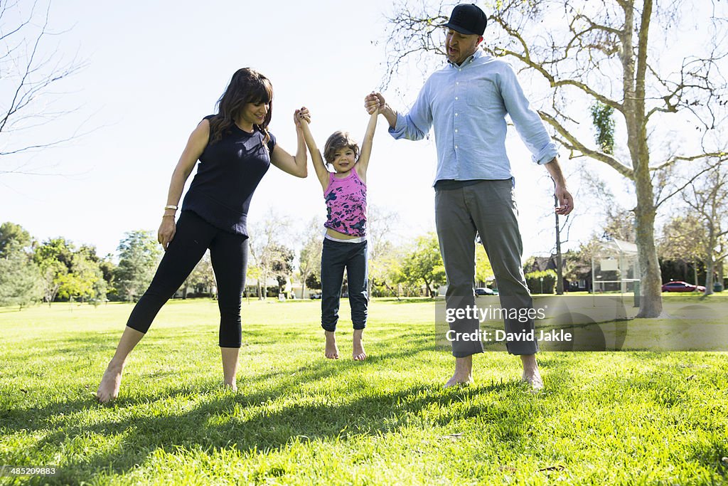 Mid adult couple lifting up young daughter in park
