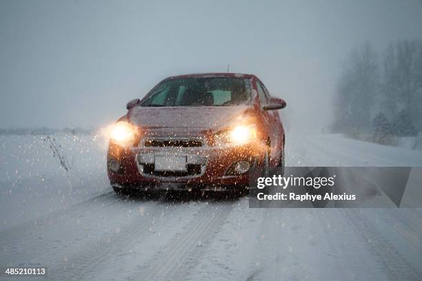 car with headlights on driving along foggy snow covered road - monroe michigan - fotografias e filmes do acervo