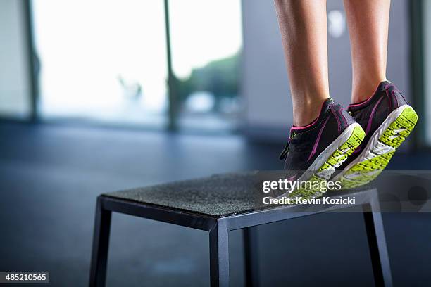 young woman tiptoeing on edge of stool - tiptoe imagens e fotografias de stock