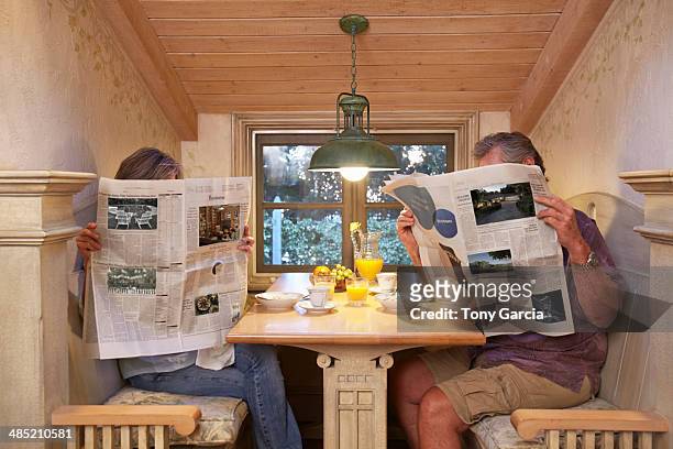 couple at breakfast table, ignoring each other, reading newspapers - viso nascosto foto e immagini stock