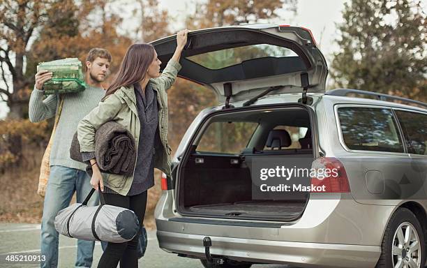 woman closing car boot while camping with man - car trunk closed stock pictures, royalty-free photos & images