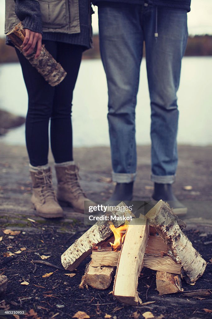 Low section of couple standing by bonfire