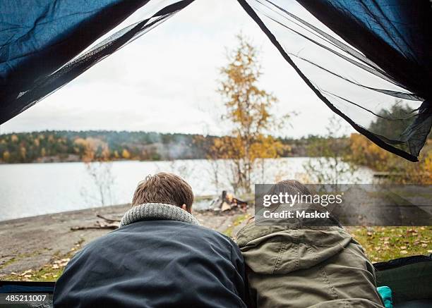 rear view of couple lying in tent at lakeshore - allongé sur le devant photos et images de collection