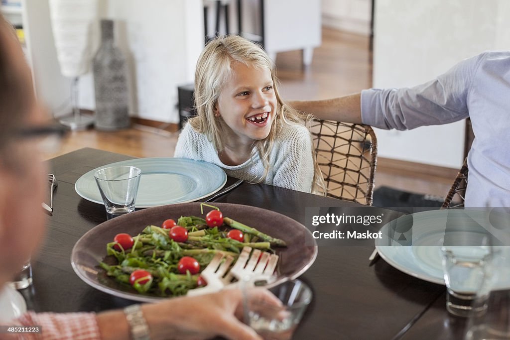 Happy girl having lunch with family at dining table