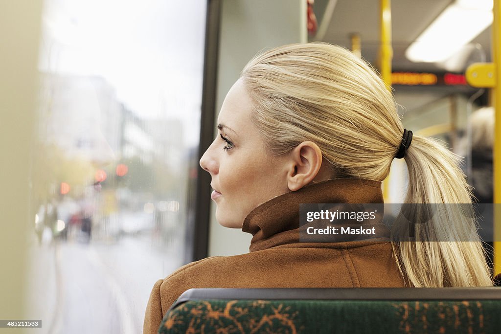 Rear view of woman looking out through bus window