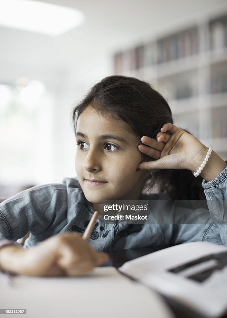 Girl looking away while studying at home