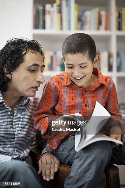 father assisting son in doing homework at home - pages turning stock pictures, royalty-free photos & images