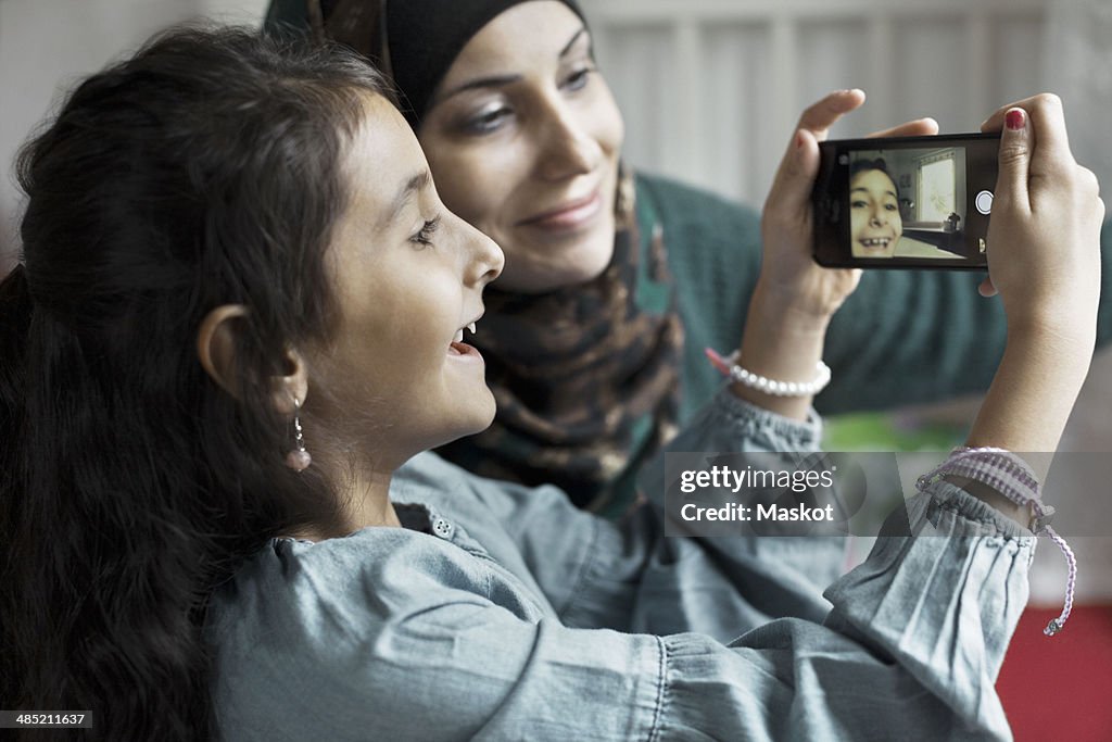 Mother and daughter taking self portrait in bedroom