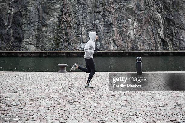 man jogging on street against rock - hooded top stock pictures, royalty-free photos & images
