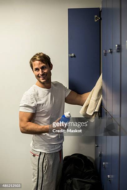 smiling man putting towel in gym's locker - spind stock-fotos und bilder