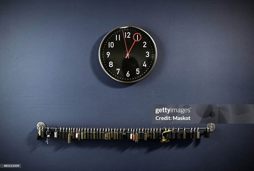 Padlocks hanging on railing with clock at gym's locker room