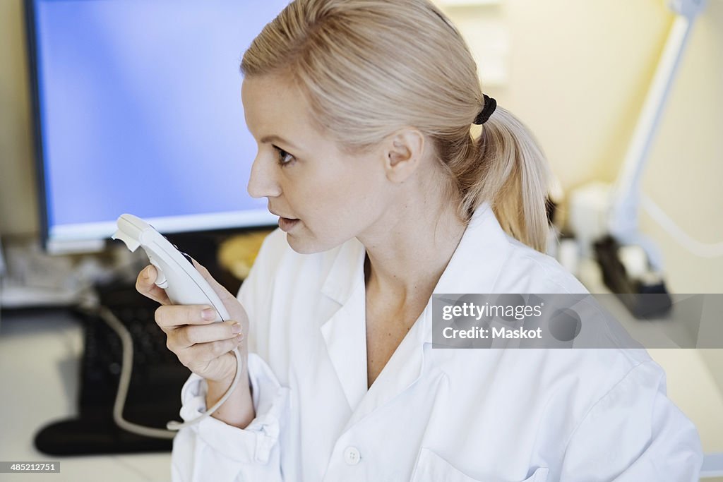 Female doctor using dictation device in office