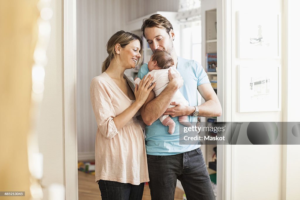 Mid adult coupe playing with baby girl at doorway