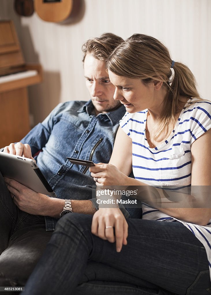 Couple shopping online with credit card and digital tablet at home