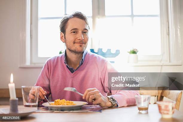 portrait of man smiling while eating pasta - sitting at table looking at camera stock-fotos und bilder