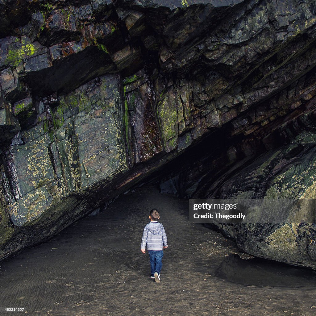 Boy standing in front of rock tunnel