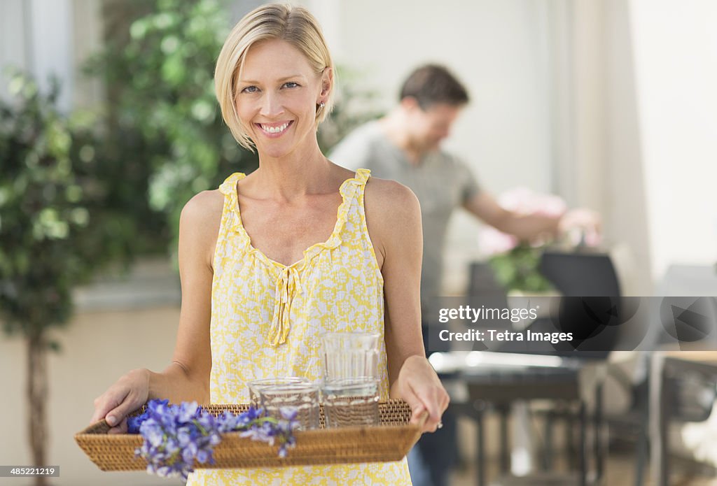 Woman carrying tray with crockery and flowers