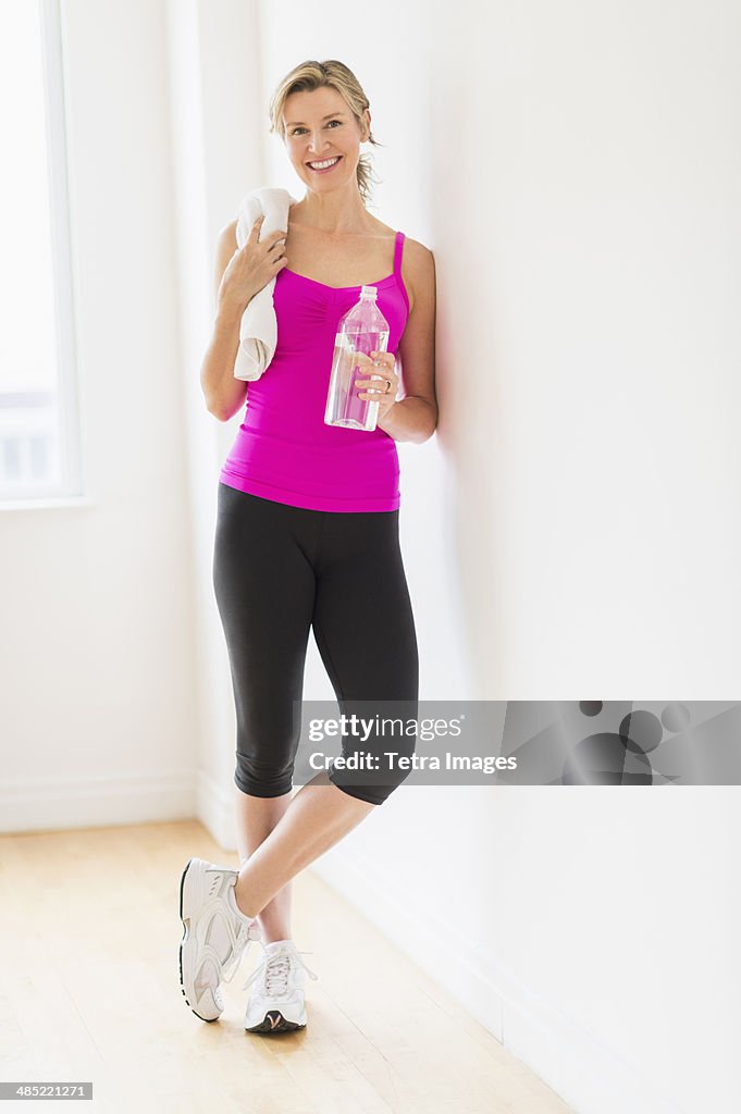 Portrait of woman in sports clothing holding water bottle