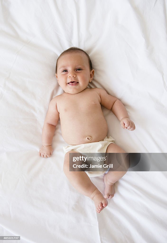 Baby girl (2-5 months) lying on bed