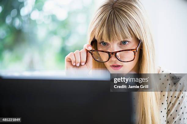 woman wearing glasses working on computer - eavesdropping stock pictures, royalty-free photos & images