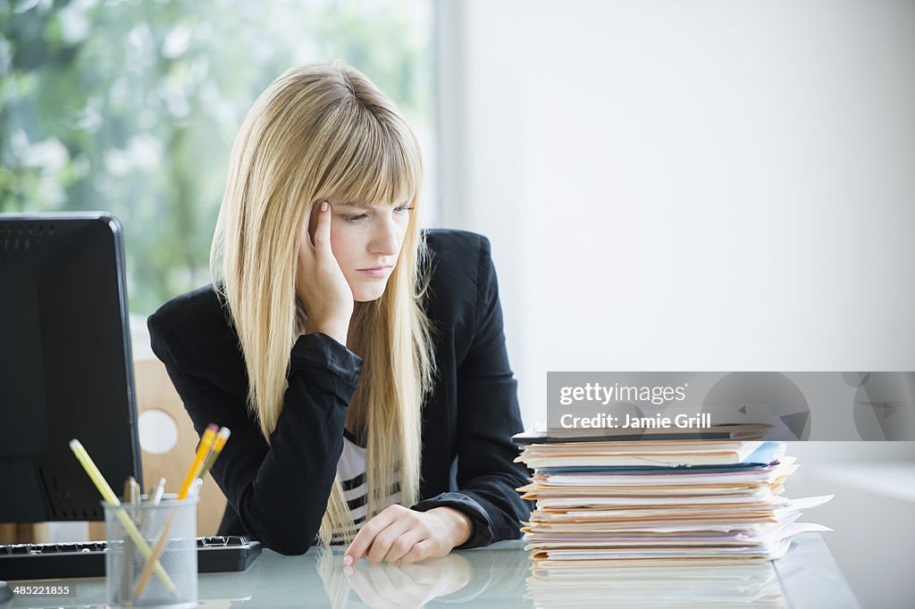 Businesswoman looking at stack of files