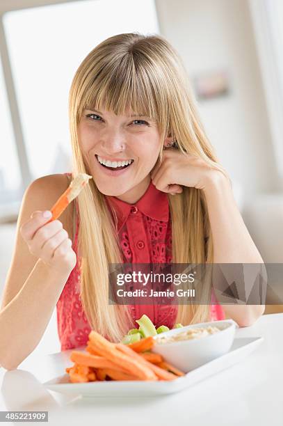 portrait of woman eating carrots - diet carrot stock-fotos und bilder