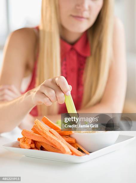 woman dipping celery - dippen stock-fotos und bilder