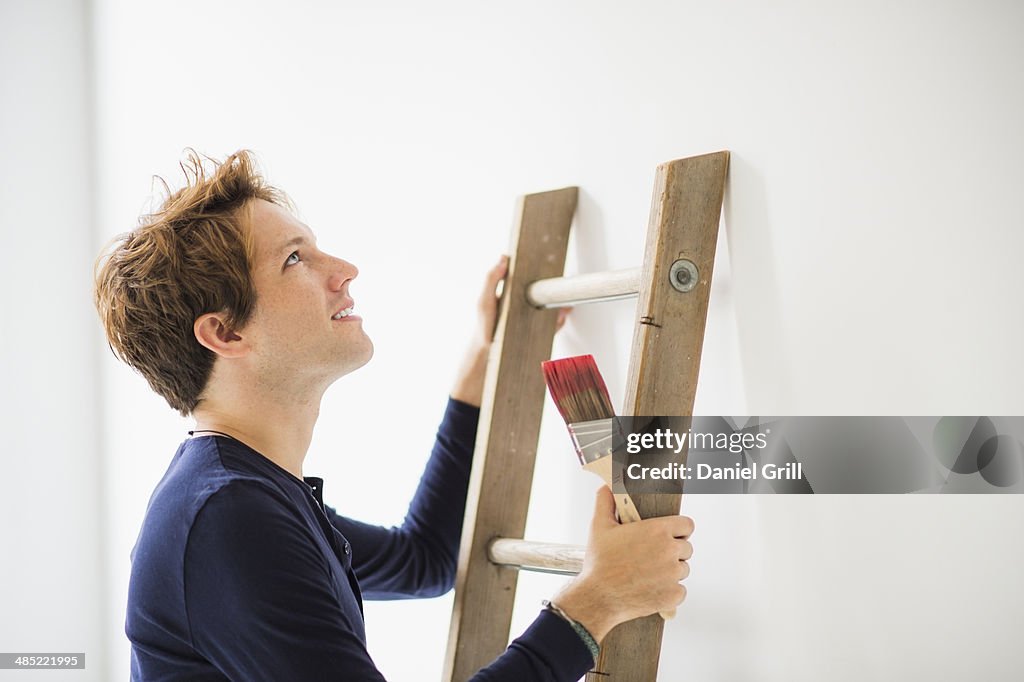 Man climbing ladder to paint wall