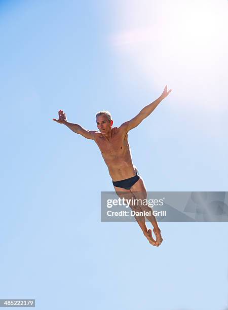 athletic swimmer mid-air against blue sky - diving platform fotografías e imágenes de stock