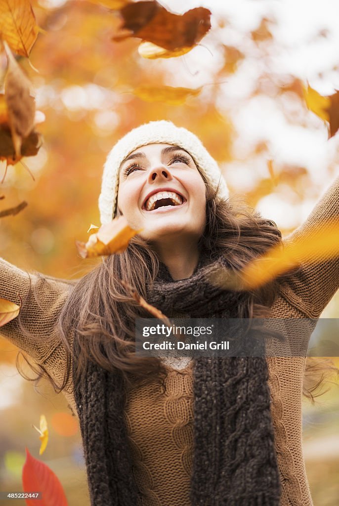 USA, New York State, New York City, Young woman playing with leaves in Central Park