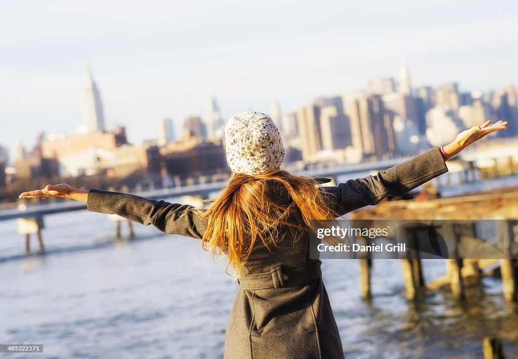 USA, New York City, Brooklyn, Williamsburg, Rear view of blond woman with arms outstretched