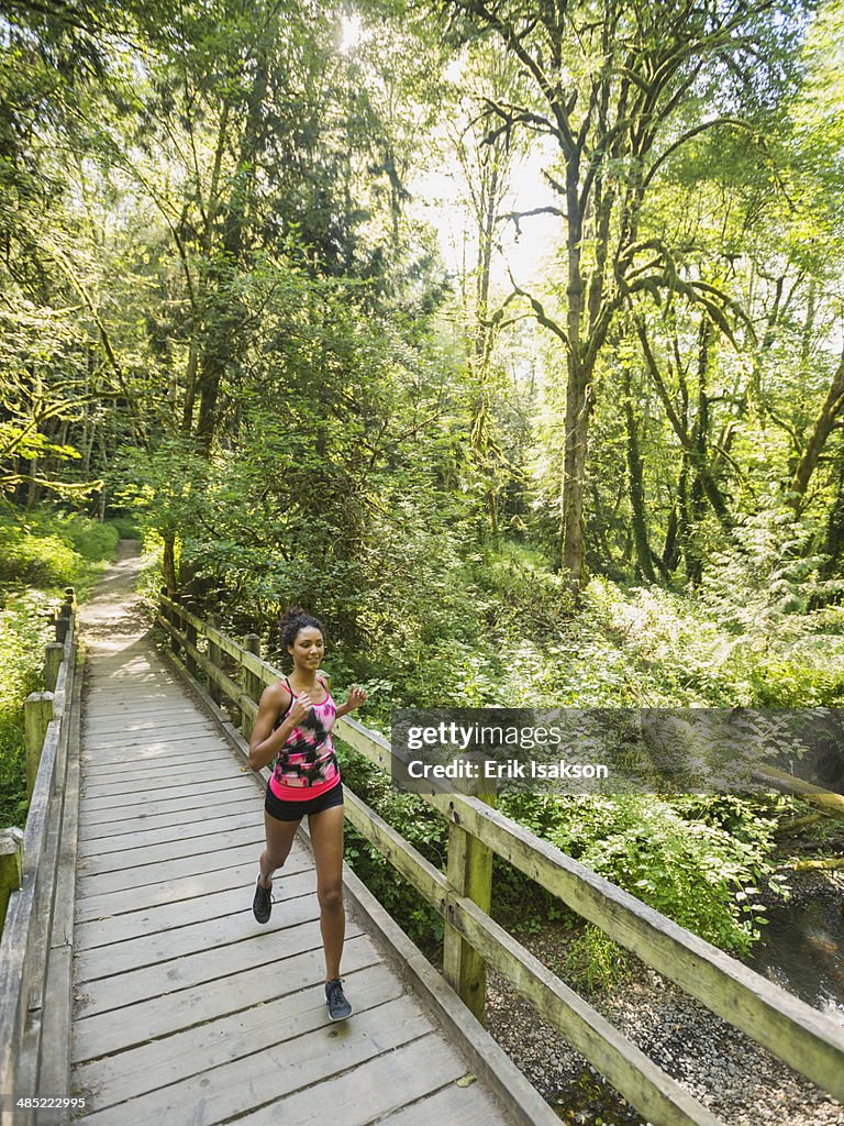 USA, Oregon, Portland, Young woman jogging on footbridge