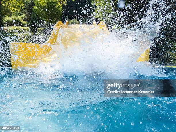 germany, thuringia, boy (6-7) making splash in pool - escorrega de água imagens e fotografias de stock