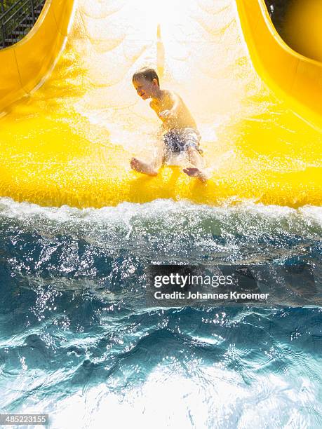 germany,thuringia, boy (6-7) having fun on water slide - tobogán de agua fotografías e imágenes de stock