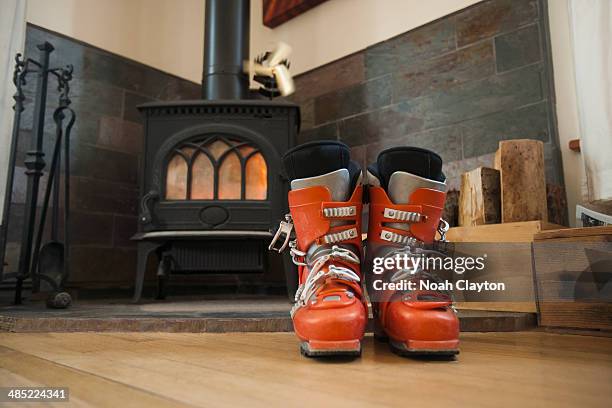usa, montana, whitefish, ski boots drying in front of fireplace - skischoen stockfoto's en -beelden