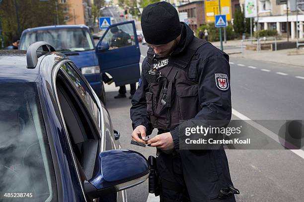 German policeman checks the vehicle documents of a motorist near the Polish border on April 15, 2014 in Frankfurt an der Oder, Germany. May 1 will...