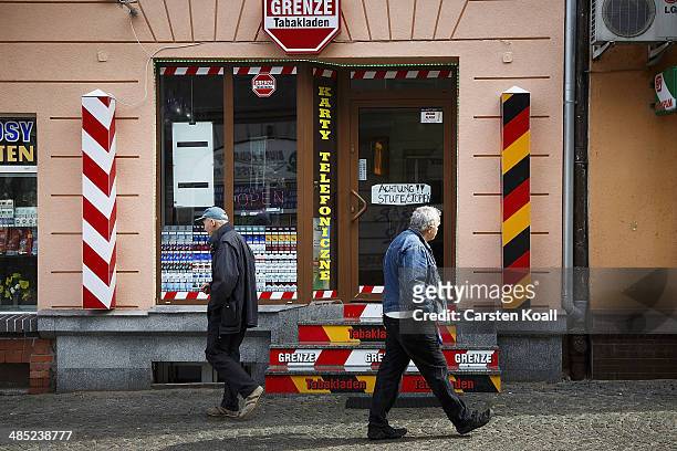 Men pass a tobacco shop showing the symbol of a german border stone on April 15, 2014 in Slubice, Poland. Slubice the first Polish city behind the...
