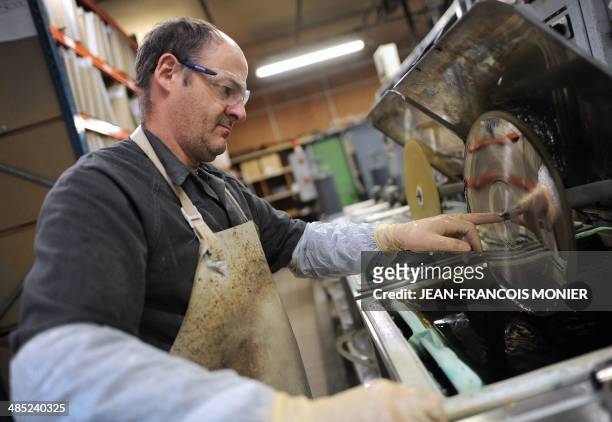By Philippe SCHWAB in French: "Le Vynile, nouvel or noir de l'industrie musicale". A worker immerses the lacquer in the electroplating tank to make...