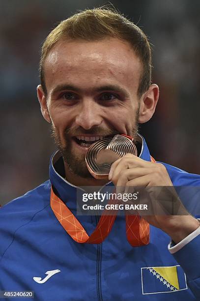 Bosnia and Herzegovina's bronze medallist Amel Tuka bites his medal on the podium during the victory ceremony for the men's 800 metres athletics...