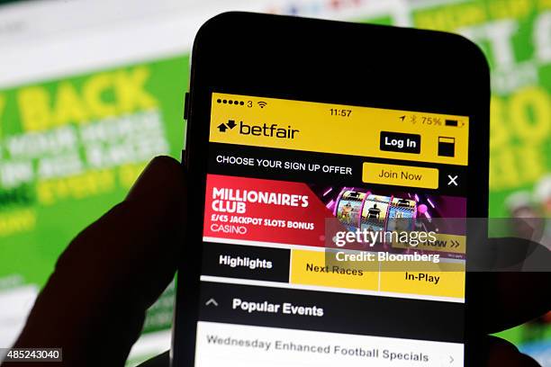 Smartphone with the Betfair Group Plc app is held in front of the Paddy Power Plc website in this arranged photograph in London, U.K., on Wednesday,...