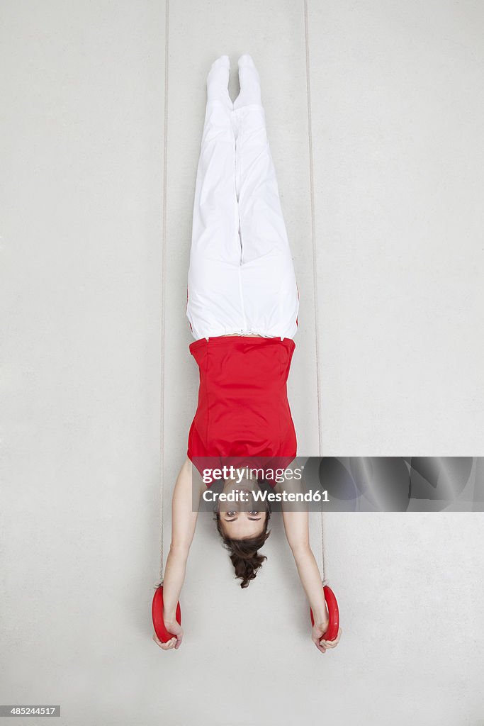 Woman exercising handstand on rings