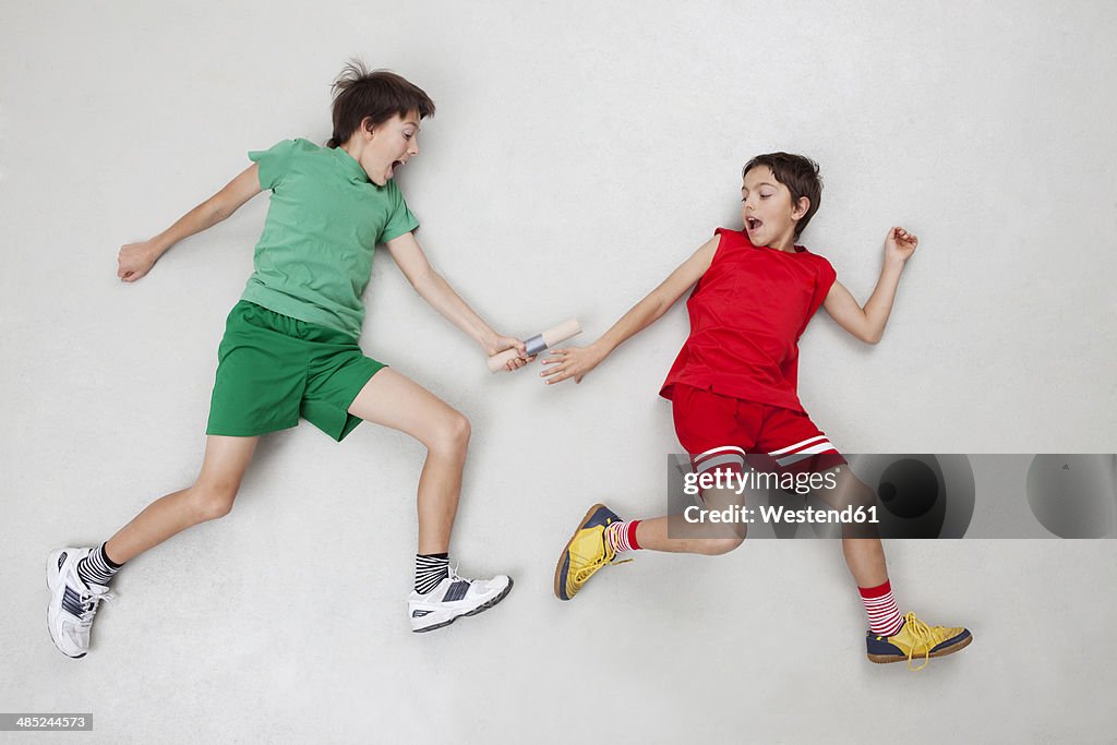 Two boys handing over baton at relay race