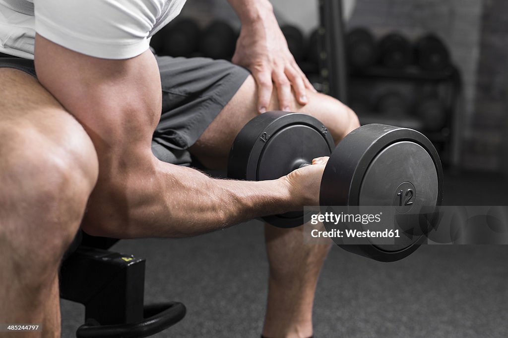 Austria, Klagenfurt, Man in fitness center training with dumbbell