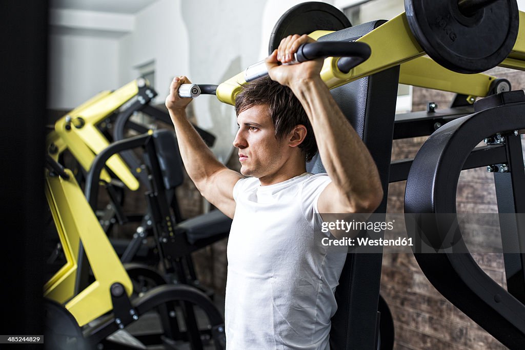 Austria, Klagenfurt, Man in fitness center doing machine workout